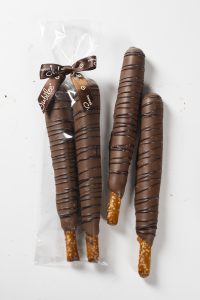two Sweet Jubilee Gourmet Pretzel rods in a gift bag and two outside of a gift bag